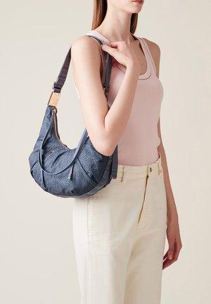 Sac hobo bleu marine avec un motif texturé, une forme incurvée, des accents en cuir et une bandoulière réglable. Fermeture éclair sur le dessus.