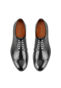 Chaussures en cuir noir avec une finition lisse, dotées d'un laçage, de bouts ronds et d'une semelle intérieure en cuir marron embossée avec "DESA."