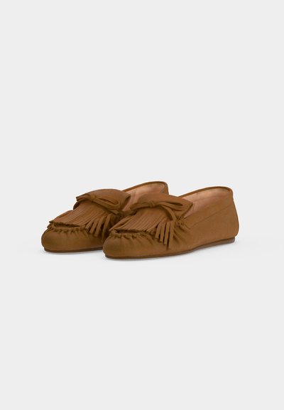 Chaussures mocassins en daim marron avec des détails à franges et des nœuds sur le dessus, inclinées vers la gauche sur fond blanc.