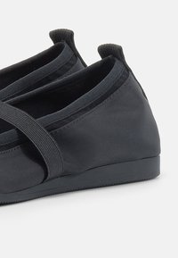 Scarpe slip-on nere realizzate in tessuto morbido con bande elastiche, dotate di una suola piatta e un design minimalista. Stile semplice e versatile.