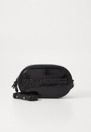 Sac oval en cuir verni noir avec logo embossé "KARL LAGERFELD JEANS", fermeture éclair et bandoulière amovible. Texture lisse.