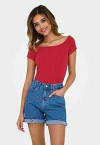 Röd kortärmad topp med off-shoulder-design, parat med högmidjade bl�å denimshorts med blommönster och upprullade ärmar.