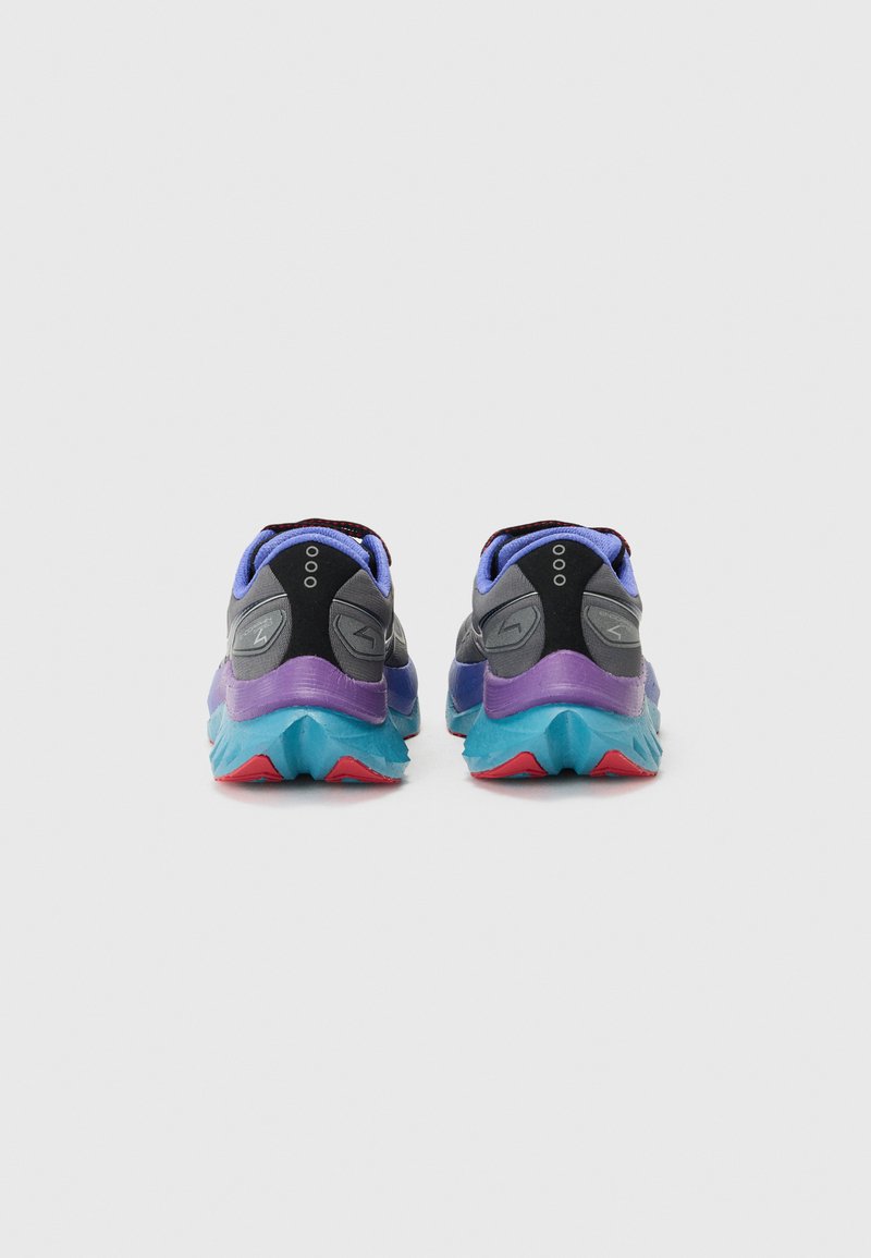 Zapatillas de correr multicolores con parte superior negra, acentos morados y una suela texturizada en teal y rojo, que cuentan con un collar acolchado y detalles del logotipo.