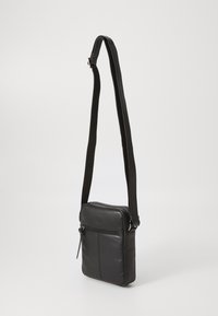 Crna kožna crossbody torba s jednim podešivim remenom, glavnim odjeljkom sa zatvaračem i prednjim džepom s vidljivim detaljima šivanja.