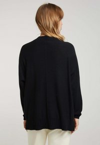Pull en maille noir à coupe ample, avec des poignets et un ourlet côtelés, un col rond et une texture lisse. La vue arrière montre un design à coupe droite.
