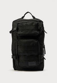 Sac à dos noir en tissu durable, doté de plusieurs compartiments, de bretelles ajustables, de fermetures éclair latérales et d'un panneau de bretelles texturé.