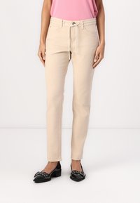 Beige, striped bukser med snøre i taljen og forlommer, stylet med sorte flade sko og en pink top.