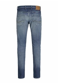 Jean bleu slim fit avec une finition délavée, cinq poches et une étiquette en cuir marron à la taille arrière. Détails de couture renforcée.