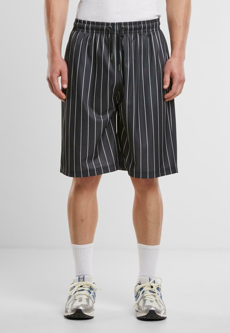 Shorts noirs à rayures fabriqués dans un matériau léger ; comprend une taille élastique avec un cordon de serrage, arrivant juste au-dessus du genou.