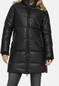 Zwarte, gewatteerde pufferjas met een hoge kraag, ritssluiting en zijzakken. Glad, glanzend faux leren materiaal. Lange mouwen met rib gebreide manchet.