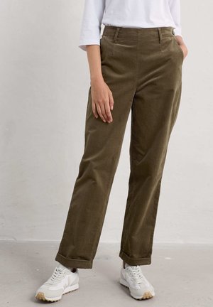 Olijfgroene corduroy broek met een rechte pasvorm, voorzien van zijzakken en opgerolde boorden, gecombineerd met witte sneakers.