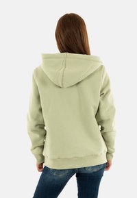 Sweat à capuche vert menthe avec une capuche spacieuse, des poignets et un ourlet côtelés. Texture douce, coutures détaillées et coupe décontractée.