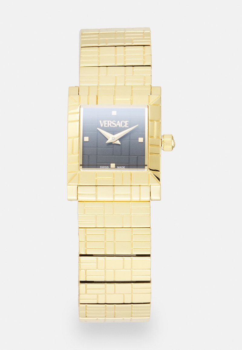 Gold rectangular watch with a textured bracelet. Features a dark square dial and gold accents, including two markers and hands.