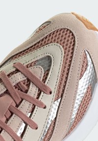 Sneaker mit einem Obermaterial aus Mesh in Hellrosa und Beige, mit silbernen Akzenten, strukturierten Wildlederpaneelen und flachen Schnürsenkeln.