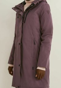 Długi, fioletowy płaszcz z kapturem, wykonany z materiału wodoodpornego. Posiada boczne kieszenie, zamek błyskawiczny oraz napy, a także elastyczne mankiety.