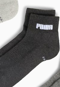 Czarna skarpetka kostkowa wykonana z mieszanki bawełny, z prążkowanym mankietem, białym logo "PUMA" na górze oraz subtelną fakturą.