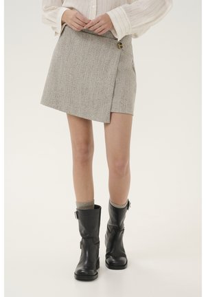 Grijze tweed wikkelrok met een knoopsluiting, met een rechte silhouet en twee zijzakken, gecombineerd met zwarte enkellaarzen.