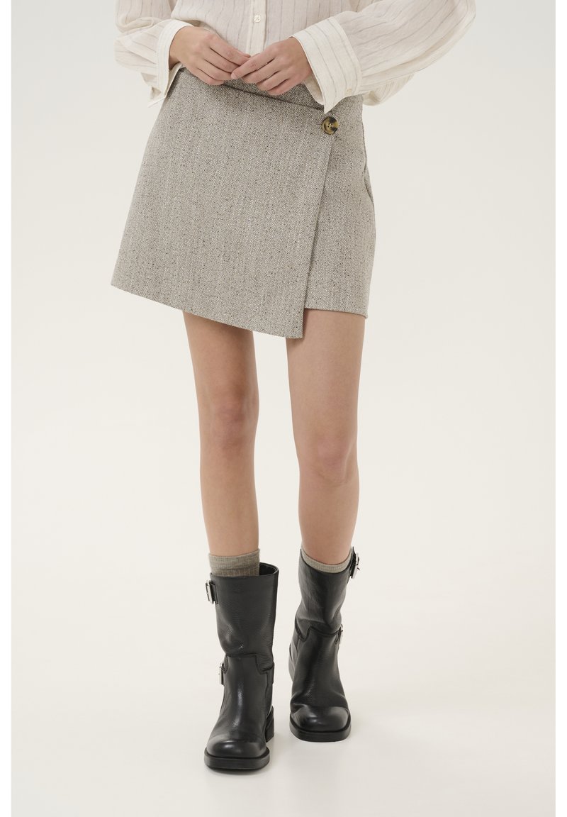 Grijze tweed wikkelrok met een knoopsluiting, met een rechte silhouet en twee zijzakken, gecombineerd met zwarte enkellaarzen.