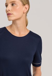 Camiseta de manga corta azul marino hecha de tela suave, con un cuello redondo y un acento blanco en el dobladillo de la manga. Diseño simple y limpio.