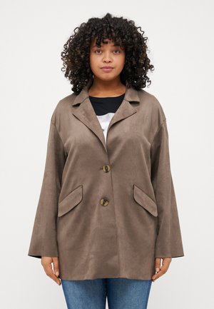 Veste en suédine brune avec un col en V, deux poches avant et deux boutons ronds ; possède des manches larges et amples ainsi qu'une texture lisse.