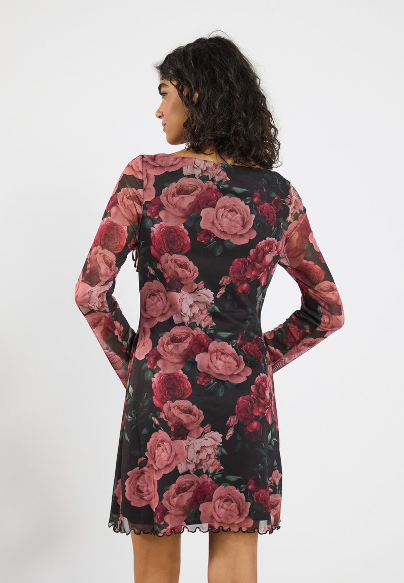 Vestido negro de manga larga, adornado con grandes motivos de rosas rosas y rojas. Presenta un dobladillo con forma de ondas y una tela lisa y ligera.