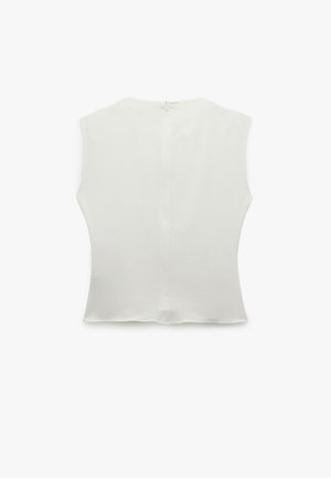 Haut sans manches blanc avec un col rond, en tissu texturé, et une couture centrale au dos, doté d'une fermeture éclair discrète.