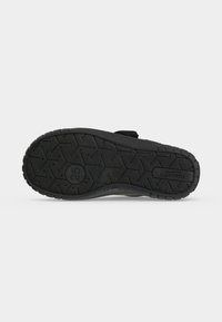 Semelle de chaussure noire avec une adhérence texturée, indication de la taille 25 et le mot superfIt embossé près du talon sur fond blanc uni.
