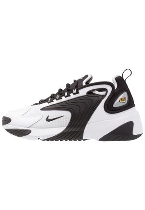 Biało-czarny sportowy sneaker z napisem "Zoom" na czarnych sznurowadłach, czarnym logo Swoosh, fakturowaną podeszwą środkową oraz oznaczeniem "Zm Air" w okolicy pięty.