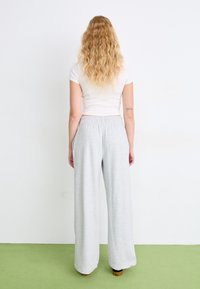Lichtgrijze wijde sweatpants gemaakt van een zachte katoenmix, met een elastische tailleband en zijzakken. Gemaakt met een relaxte pasvorm.
