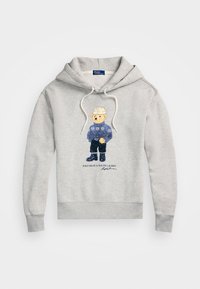 Súdadera gris con un gráfico de un oso con un suéter azul, pantalones negros y un sombrero. Cuello con cordón y puños y dobladillo acanalados.