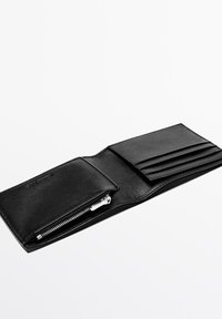 Czarny skórzany portfel z zamykaną na zamek kieszenią, wieloma przegródkami na karty i gładką fakturą. Charakteryzuje się minimalistycznym designem oraz srebrnymi ozdobami.