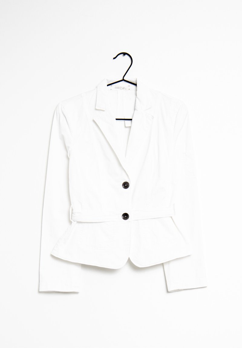 Blazer blanc cintré avec deux boutons noirs, revers crantés et bas peplum suspendu sur un cintre noir sur fond blanc.