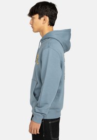 Felpa blu chiaro con tasca a kangaroo, cappuccio con cordino e polsini a coste. Presenta un design grafico frontale giallo. Vestibilità casual.