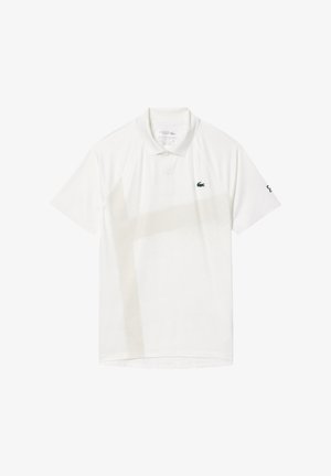 Vit polo-tröja i tyg med ett subtilt beige diagonalt mönster, grön logotyp på vänster bröst och varumärkesdetalj på ärmen.