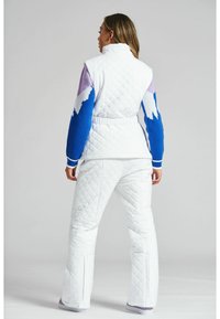 Gep quilteter weißer Winteranzug mit lila und blauen gemusterten Ärmeln, tailliertem Schnitt, seitlichen Schlitzen an den Hosen und Rippenelementen an den Bündchen.