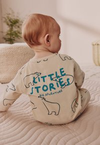 Helbed beežikangast pidžaamad karu kontuuridega ja sinine tekst "VÄIKSED LUGUDED SUUR SEIKLUS." Pehme tekstuur, ümara kaelusega.