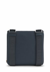 Granatowa torebka na ramię o gładkiej fakturze, wyposażona w suwaki i materiałowy pasek z wytłoczonym logo "BOSS".