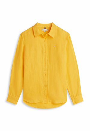 Camicia gialla a maniche lunghe con collo, piccolo logo del marchio sul petto a sinistra e orlo leggermente curvato nella parte inferiore.