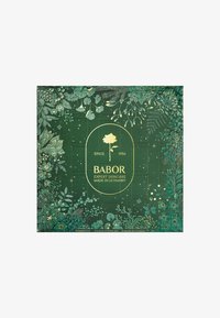Green skincare advent calendar with gold accents, featuring botanical illustrations and numbered openings. Text reads: "Babor Expert Skincare."
