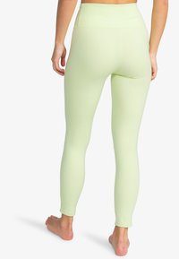 Lichtgroene high-waisted leggings, met een gladde textuur, aansluitend ontwerp, reikt tot de enkels, zonder zichtbare patronen of hardware.