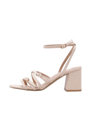 Sandalia beige de tacón de bloque con tres tiras delanteras, cada una con una pequeña hebilla, y una correa en el tobillo con cierre de hebilla dorada.