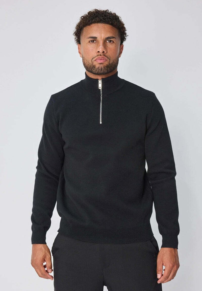 Pull noir en maille avec un col haut et une fermeture éclair argentée, doté de manches longues et d'un ourlet ajusté. Design simple et polyvalent.