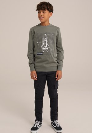 Grå långärmad sweatshirt med en vit grafik av ett rymdskepp och rutmönster, i kombination med svarta cargobyxor och svarta sneakers.