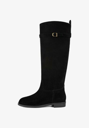 Čierne semišové čižmy po kolená s okrúhlou špičkou, plochým opätkom a ozdobným pásikom s zlatým prackou na vrchu.