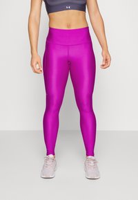 Leggings rosa attillati realizzati in un tessuto morbido ed elastico con una vita alta; abbinati a scarpe sportive grigio chiaro.