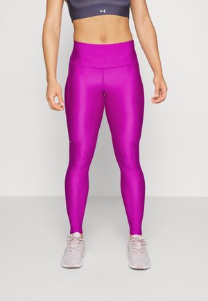 Leggings rosa attillati realizzati in un tessuto morbido ed elastico con una vita alta; abbinati a scarpe sportive grigio chiaro.