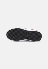 Čierna gumová podrážka s textúrovaným gripom, biela medzipodrážka a oranžový akcent pri päte, navrhnutá na používanie pri skateboarding.