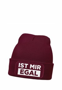 Maroon knitted beanie with a folded cuff, featuring a patch with the text "IST MIR EGAL" in white and black. Soft, textured fabric.