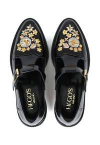 Czarne lakierowane buty ze wzorem kwiatowym w kolorze kości słoniowej, złotym i żółtym. Posiadają design z paskiem T i złote akcenty z klamrami.