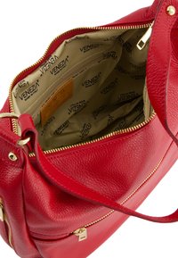 Rote Lederhandtasche mit strukturiertem Außenmaterial und goldenen Reißverschlussdetails. Das Innere ist mit einem beigen Futter und wiederholten Logos ausgestattet.